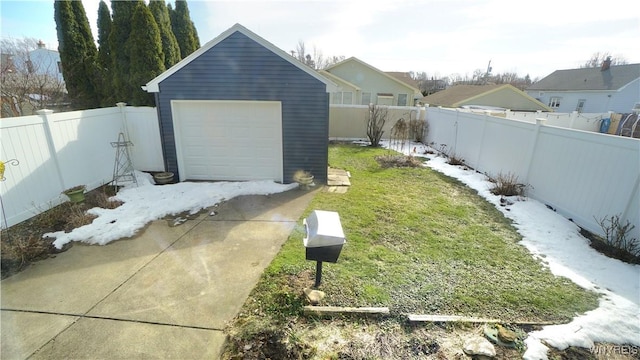 view of yard with a garage, concrete driveway, an outdoor structure, and a fenced backyard