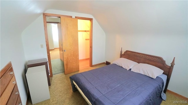 bedroom with lofted ceiling and baseboards