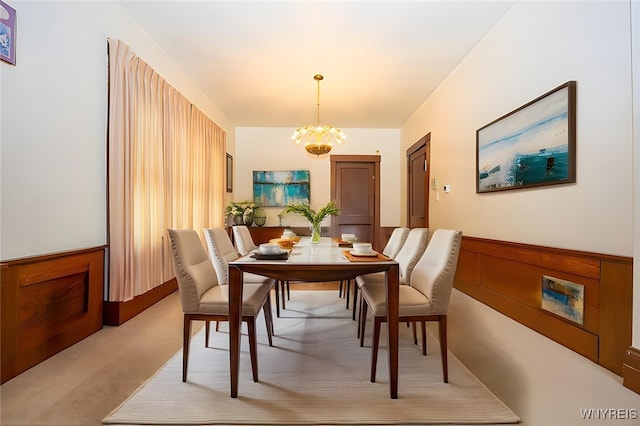 dining room featuring light carpet and a chandelier