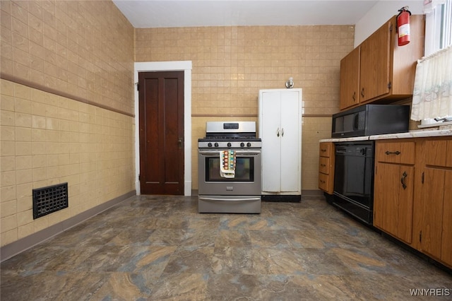 kitchen with visible vents, black appliances, light countertops, and tile walls