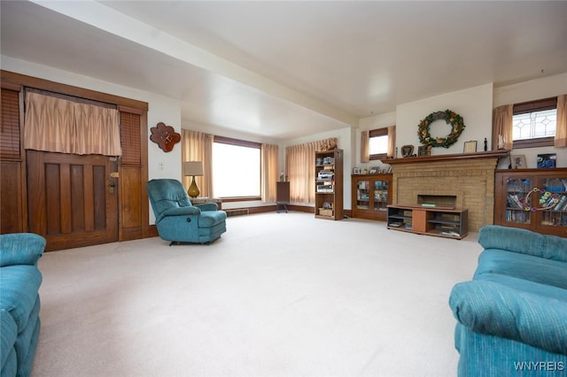 living area with carpet floors, a brick fireplace, a healthy amount of sunlight, and visible vents