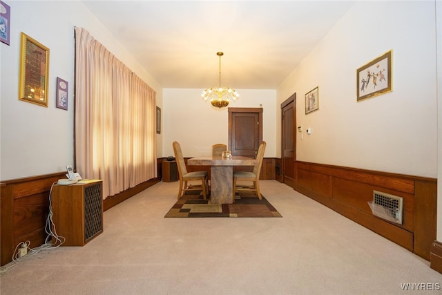 dining space with a chandelier, light colored carpet, a wainscoted wall, and visible vents