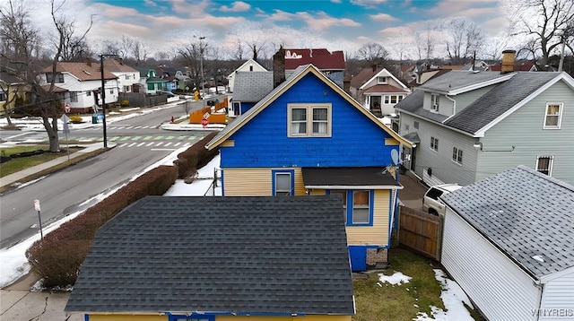 exterior space featuring a residential view, fence, and roof with shingles