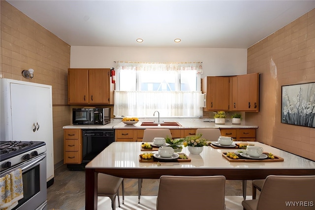 kitchen with stainless steel gas range oven, a sink, tile walls, black dishwasher, and light countertops