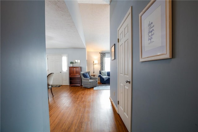 corridor featuring a textured ceiling and wood finished floors