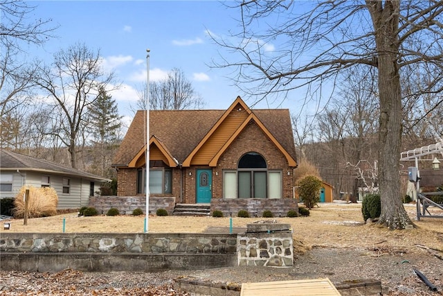 view of front of house with roof with shingles and brick siding