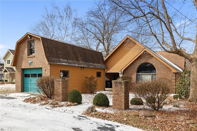 view of front of house with a garage, brick siding, a shingled roof, and a gambrel roof