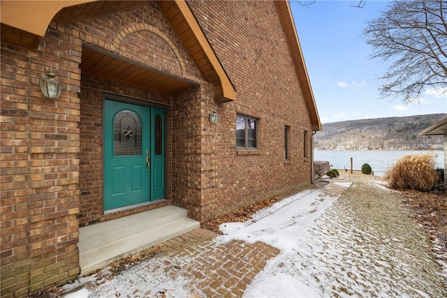 property entrance with a water view and brick siding