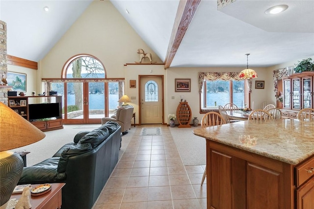 kitchen featuring french doors, light tile patterned floors, open floor plan, high vaulted ceiling, and plenty of natural light