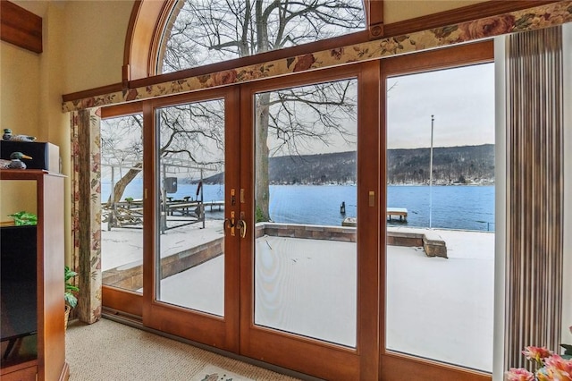 doorway to outside featuring a water view, carpet, plenty of natural light, and french doors