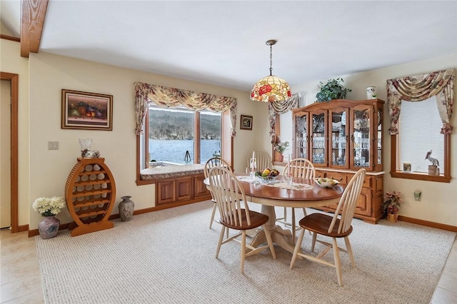 dining space featuring a water view and baseboards