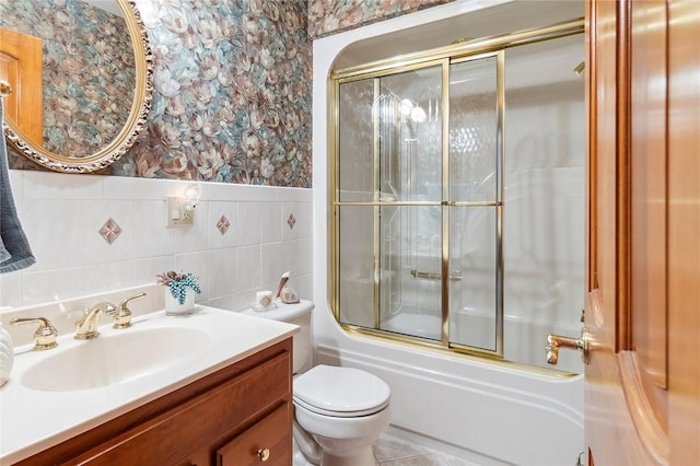 full bath with shower / bath combination with glass door, tile walls, toilet, vanity, and wallpapered walls