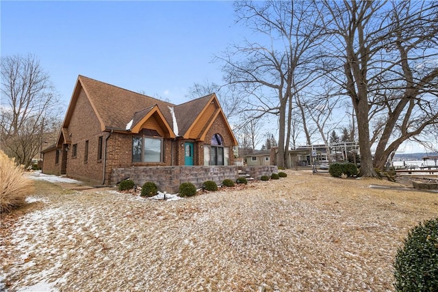 view of side of home featuring roof with shingles and brick siding