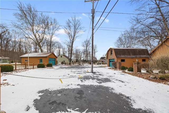 yard layered in snow with a garage and an outbuilding