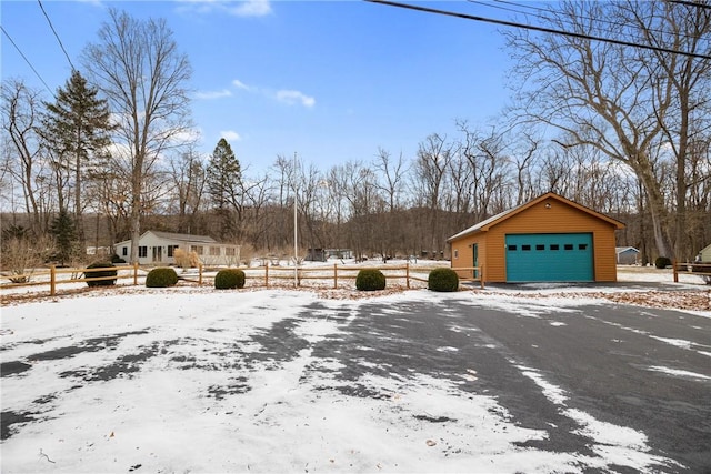 snowy yard featuring a garage and an outbuilding