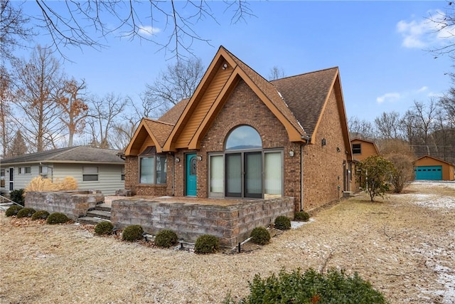 view of front of home with a shingled roof and brick siding