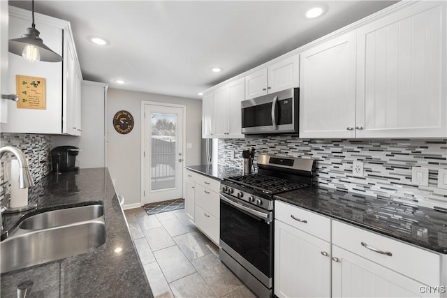 kitchen featuring stainless steel appliances, a sink, white cabinetry, backsplash, and pendant lighting