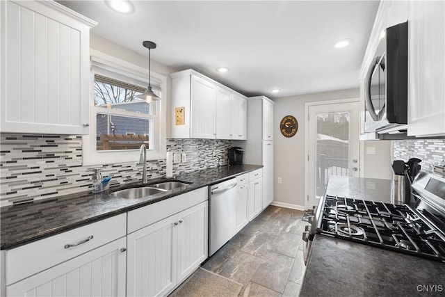 kitchen featuring baseboards, decorative backsplash, appliances with stainless steel finishes, white cabinetry, and a sink