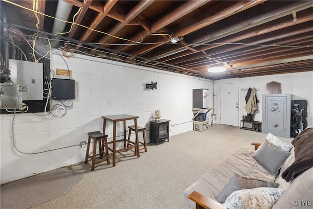 unfinished below grade area featuring a wood stove, electric panel, and carpet flooring