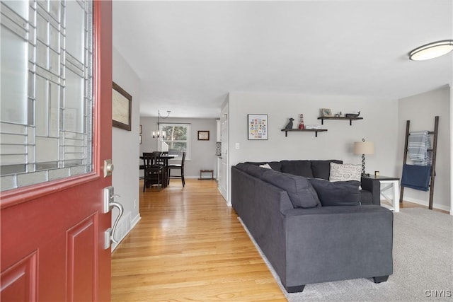 living area featuring light wood-style flooring, a chandelier, and baseboards