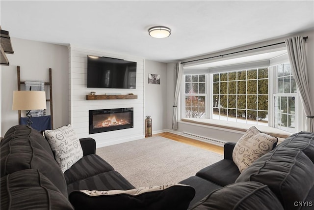 living room featuring visible vents, a fireplace, baseboards, and wood finished floors