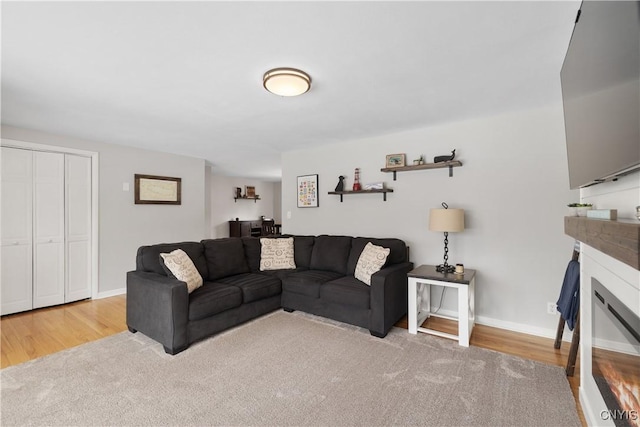 living room featuring baseboards, wood finished floors, and a glass covered fireplace