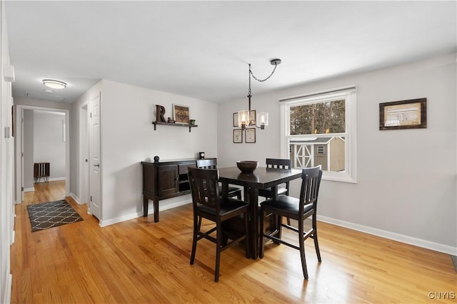 dining space with a chandelier, light wood-style flooring, and baseboards