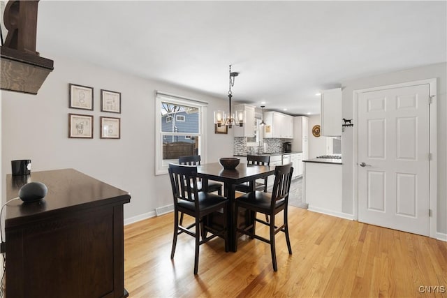 dining space featuring baseboards, light wood-style flooring, and an inviting chandelier