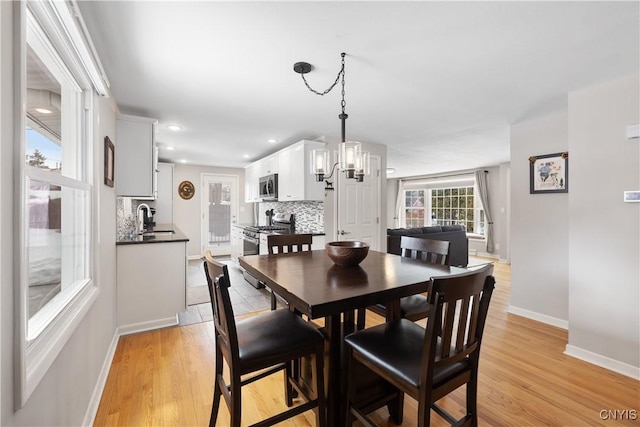 dining space featuring light wood-style floors, recessed lighting, a chandelier, and baseboards