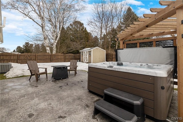 view of patio featuring an outbuilding, a fenced backyard, a storage shed, central AC, and a hot tub