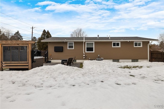 snow covered house featuring a gate, fence, and a wooden deck