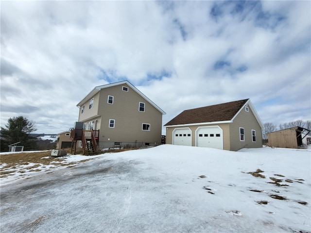 view of snowy exterior with a detached garage and an outdoor structure