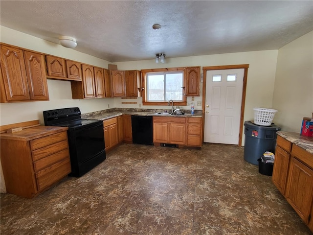 kitchen with black appliances, a textured ceiling, brown cabinets, and a sink