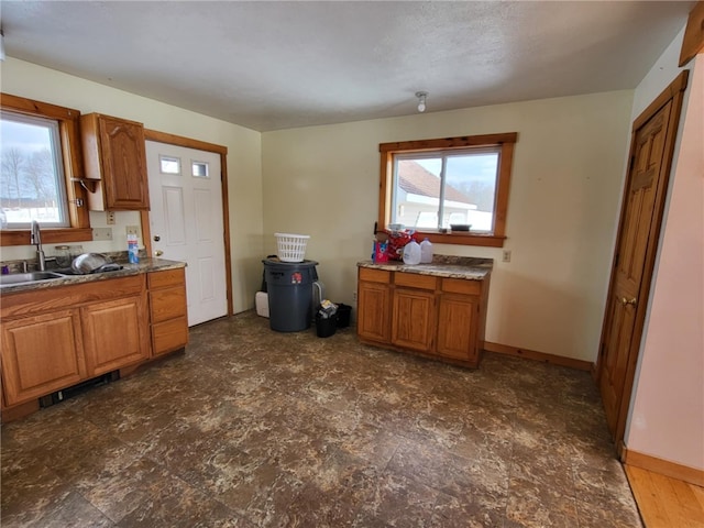 kitchen with baseboards, brown cabinets, and a sink