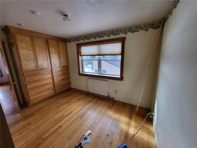 unfurnished bedroom with radiator and light wood finished floors