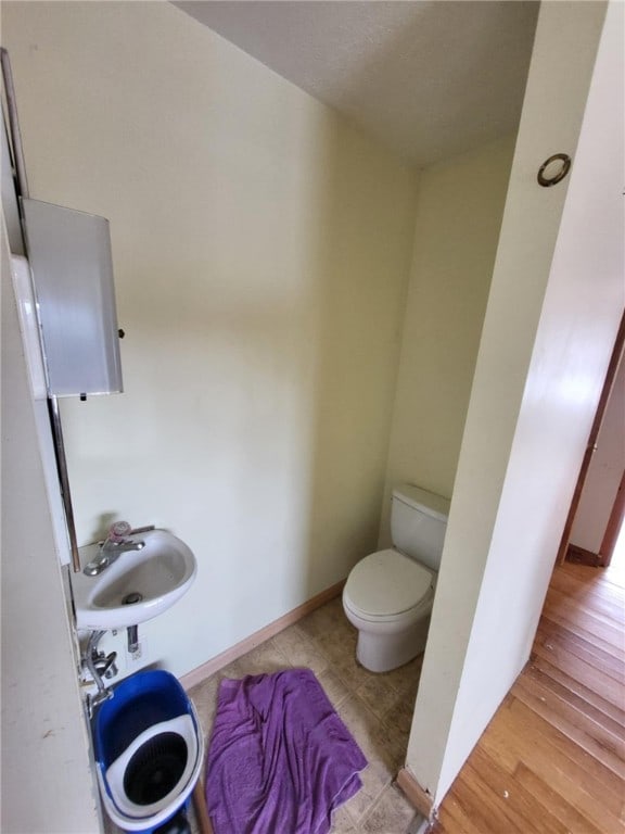 bathroom with toilet, baseboards, and a sink