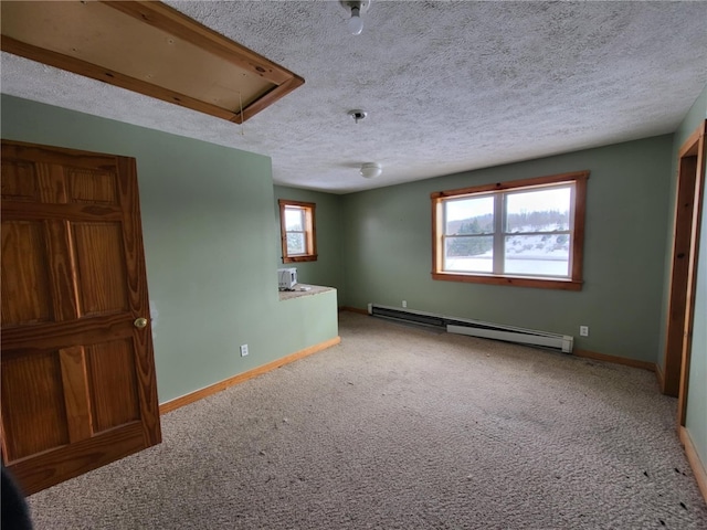 carpeted spare room featuring a textured ceiling, a baseboard radiator, attic access, and baseboards