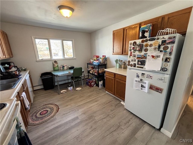 kitchen featuring light wood-style floors, brown cabinetry, a sink, and freestanding refrigerator