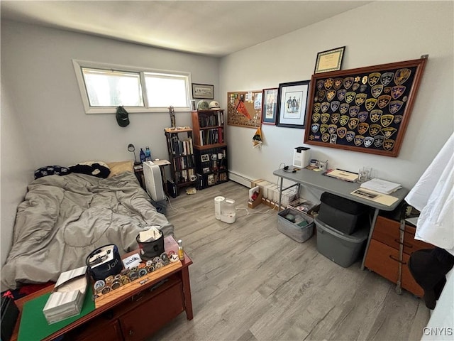 bedroom featuring a baseboard heating unit and wood finished floors