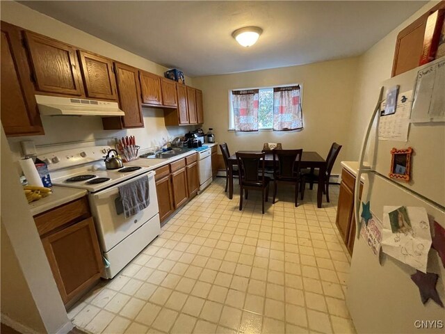 kitchen featuring under cabinet range hood, white appliances, a sink, light countertops, and brown cabinets