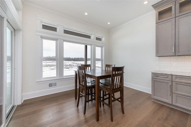 dining room featuring dark wood-style flooring, crown molding, recessed lighting, visible vents, and baseboards