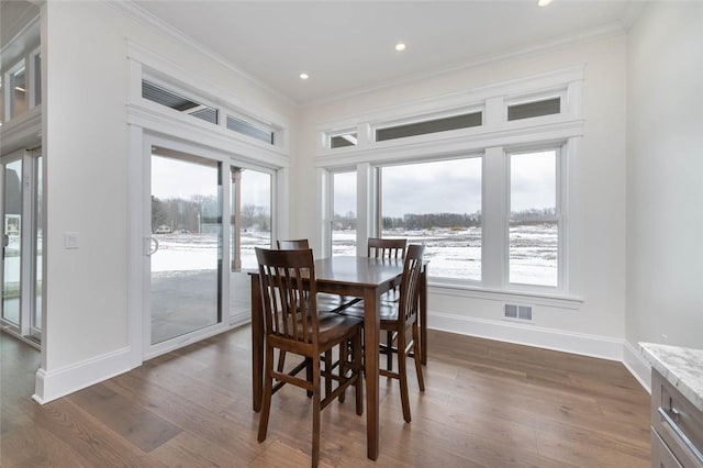 dining space with a wealth of natural light, dark wood finished floors, crown molding, and baseboards