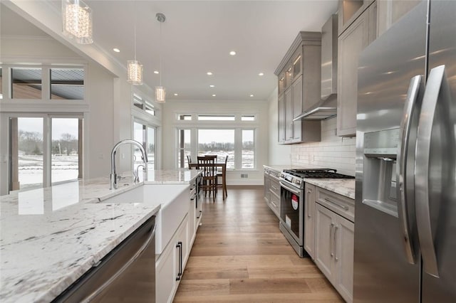 kitchen featuring wall chimney range hood, appliances with stainless steel finishes, ornamental molding, and gray cabinetry