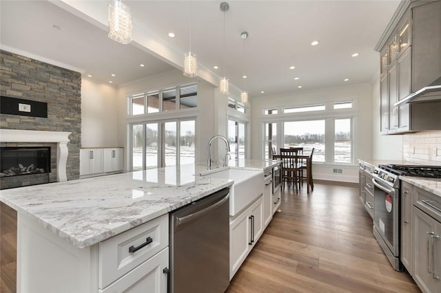 kitchen featuring backsplash, appliances with stainless steel finishes, light wood-style floors, open floor plan, and ornamental molding