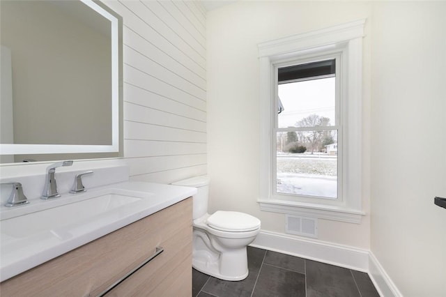 half bath featuring toilet, baseboards, visible vents, and vanity