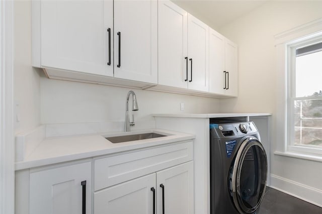 laundry room featuring washer / clothes dryer, a sink, cabinet space, and baseboards