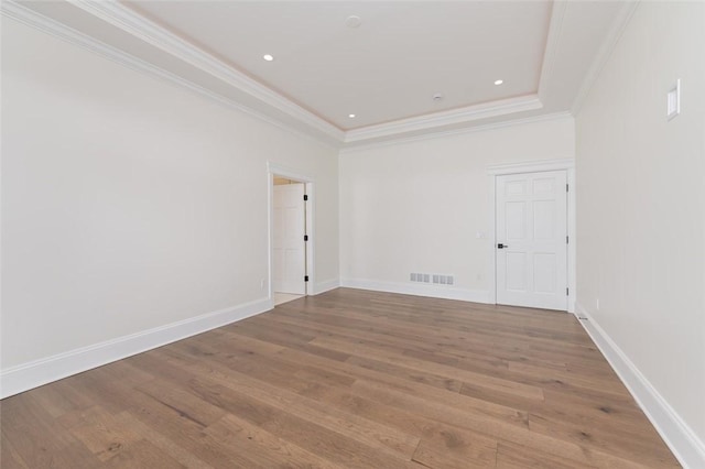 unfurnished room with baseboards, visible vents, wood finished floors, crown molding, and recessed lighting