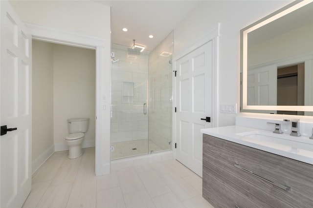 bathroom featuring a stall shower, baseboards, toilet, vanity, and recessed lighting