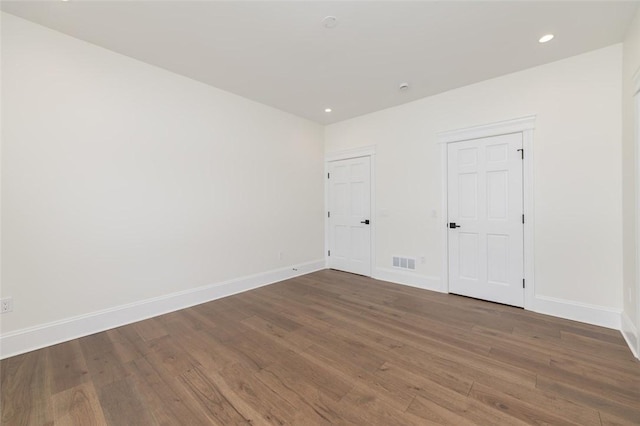 empty room featuring visible vents, baseboards, wood finished floors, and recessed lighting