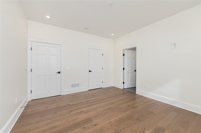 unfurnished bedroom with recessed lighting, wood finished floors, visible vents, and baseboards